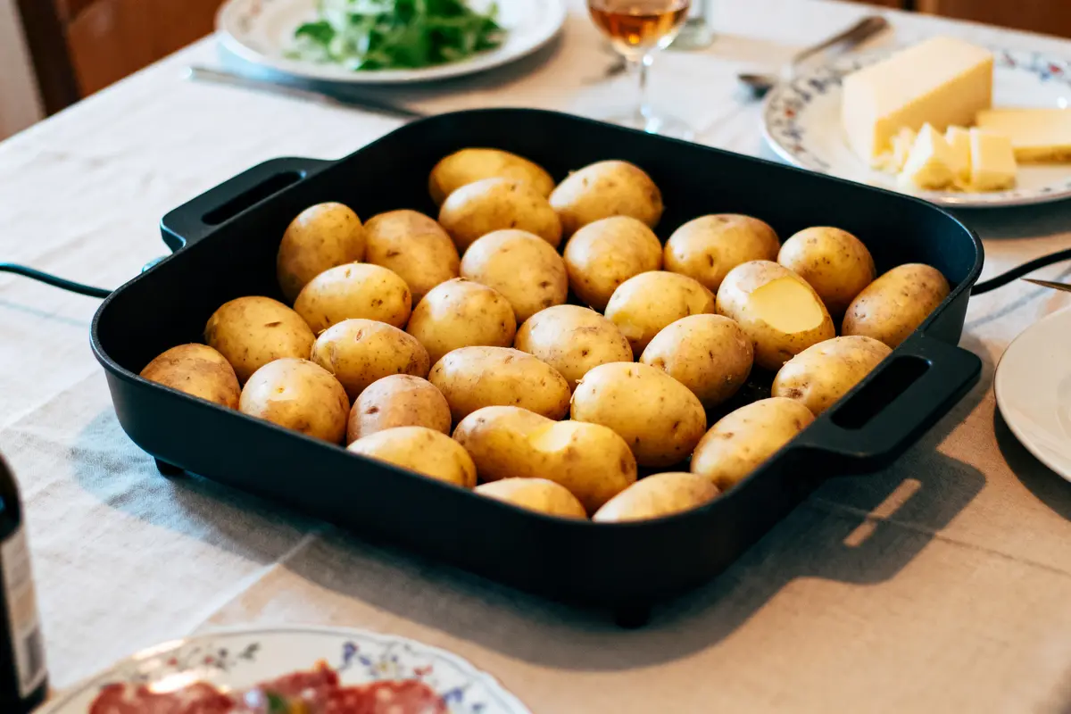 Plat de pommes de terre crues dans un grand plat noir sur une table dressée.