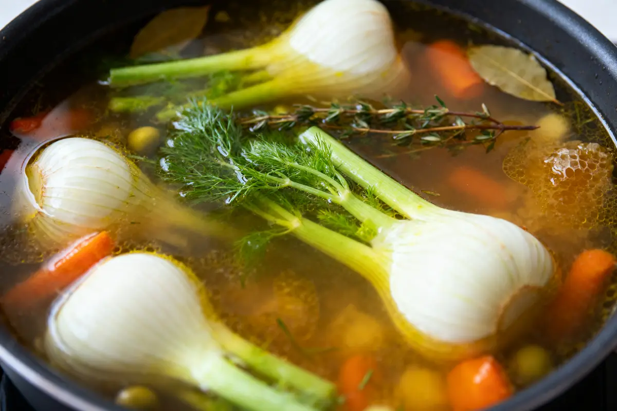 Bouillon de légumes avec fenouil, carottes, herbes, laurier et épices dans une casserole.