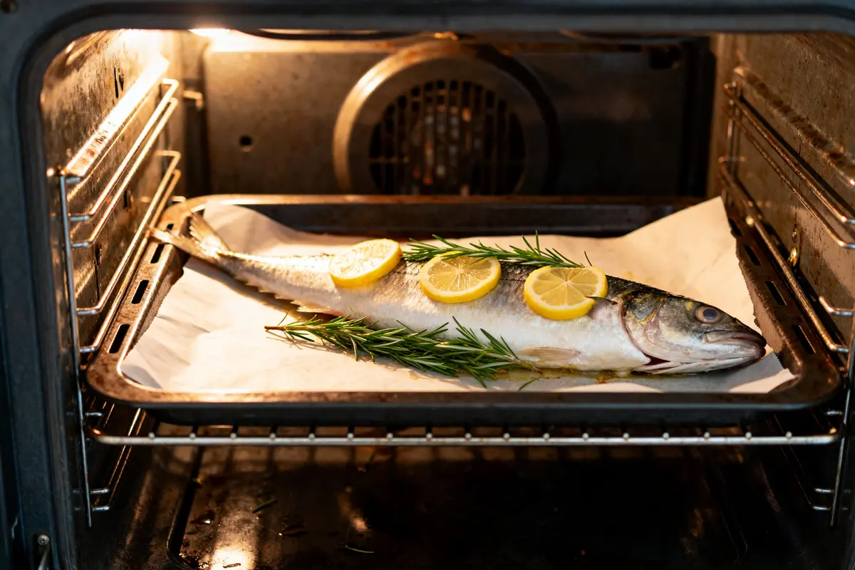 Bar cuisson au four avec tranches de citron et romarin sur plaque de cuisson